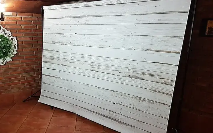 Fotomatón de tótem abierto con impresora junto a un photocall en el salón de una boda