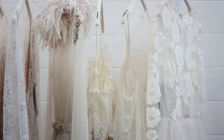 Vestido de novia largo colgado de una percha junto a una ventana