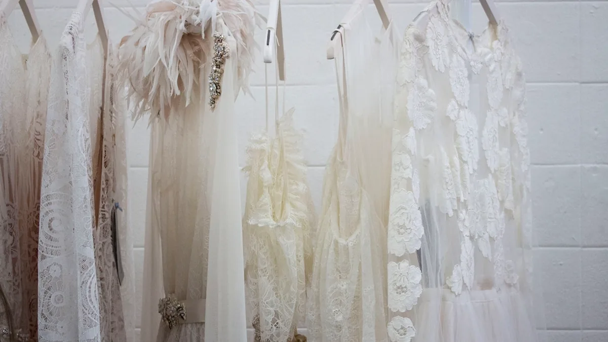 Vestido de novia largo colgado de una percha junto a una ventana
